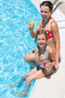 Photo: mother and daughter sitting on edge of pool with drink mother and daughter sitting on edge of pool with drink