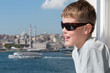 Boy in sunglasses against landscape with river and mosque
