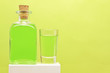 Peppermint liqueur bottle and shot on green background