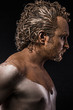 man covered in mud, naked, in profile