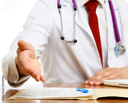 Photo: Unknown male doctor with stethoscope sitting at desk isolated Unknown male doctor with stethoscope sitting at desk isolated