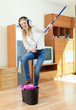 Happy housewife in headphones washing floor