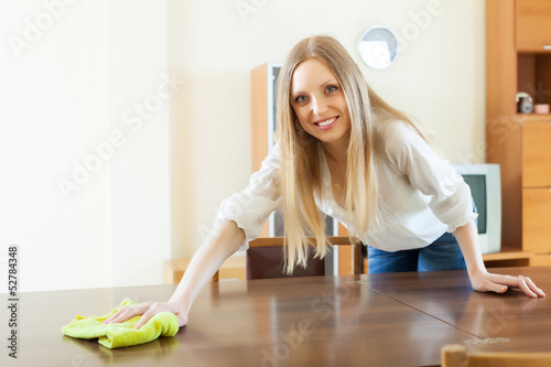Photo: Happy long-haired woman wiping the table Happy long-haired woman wiping the table