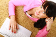 A young girl with a laptop lying on the floor
