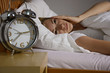 Junge Frau liegt nachdenklich im Bett