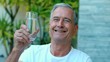Retired man toasting with water outside