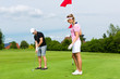Photo: Young sportive couple playing golf on a course Young sportive couple playing golf on a course