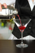 Barmen hand with shaker  pouring cocktail into glass,