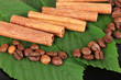 Coffee grains and cinnamon on sackcloth on green leafs close-up