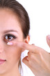 Young woman putting contact lens in her eye close up