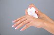 Woman applying cream on hands on color background