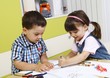 Two preschool children playing with crayons