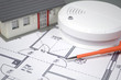 Rauchmelder mit Bauplan und Haus