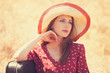 Redhead girl with suitcase sitting at grass