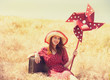 Redhead girl with suitcase and wind turbine sitting at grass