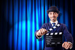 Man with movie clapper on curtain background