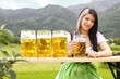 junge Frau im Dirndl in den Bergen mit Maß Bier