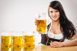 Frau sitzt am Biertisch mit Maßkrügen und prostet zu