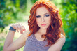 Summer portrait of a beautiful girl with long curly red hair