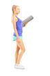 Photo: Young female athlete holding an exercising mat Young female athlete holding an exercising mat