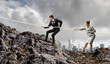 Two businessmen pulling rope atop of mountain