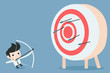 businessman aiming at target with bow and arrow