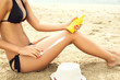 woman moisturizing applying sun cream on her tanned body and leg