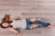 Beautiful woman with headphones lying on the floor
