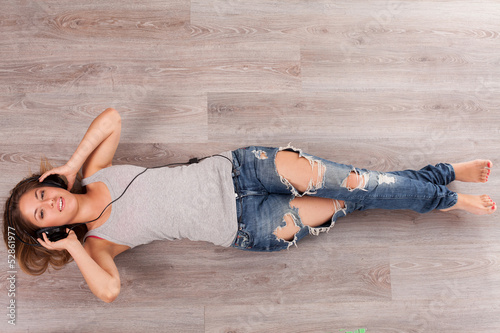 Photo: Beautiful woman with headphones lying on the floor Beautiful woman with headphones lying on the floor