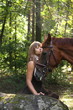 Beautiful girl and brown horse portrait in mysterious forest