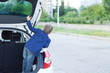 Child standing in the open trunk of a car