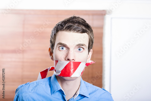 Photo: Businessman in silence with red warning tape Businessman in silence with red warning tape