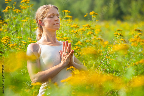Photo: woman practicing yoga in meadow of yellow flowers woman practicing yoga in meadow of yellow flowers