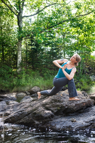 Photo: woman practicing yoga on rocks beside stream woman practicing yoga on rocks beside stream