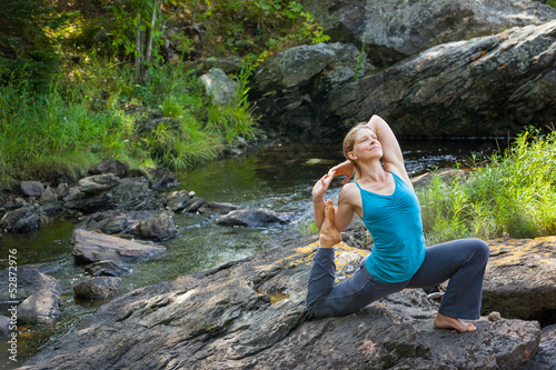Photo: woman practicing yoga on rocks beside stream woman practicing yoga on rocks beside stream