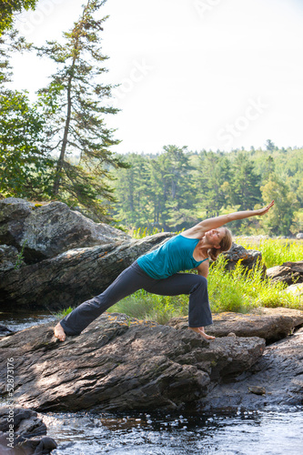 Photo: woman practicing yoga on rocks beside stream woman practicing yoga on rocks beside stream