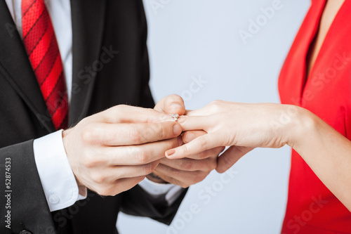 Photo: man putting wedding ring on woman hand man putting wedding ring on woman hand