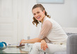 Photo: Portrait of smiling housewife sitting on couch in living room Portrait of smiling housewife sitting on couch in living room