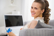 Photo: Smiling young housewife with laptop and credit card Smiling young housewife with laptop and credit card