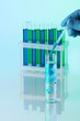 Identical test tubes and hand on blue background