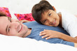 Father And Son Lying In Bed Together