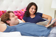 Couple Relaxing In Bed Wearing Pajamas And Reading Newspaper