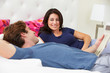 Couple Relaxing In Bed Wearing Pajamas And Reading Newspaper