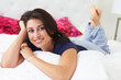 Woman Relaxing In Bed Wearing Pajamas