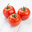 Three fresh red tomatoes on wooden boards, studio shot