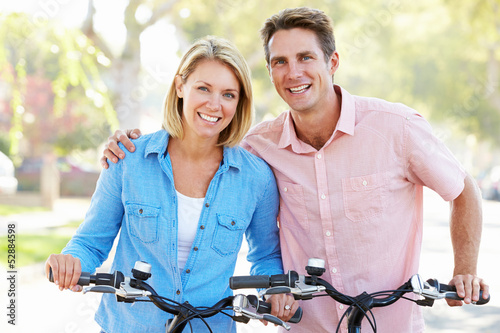 Photo: Couple Cycling On Suburban Street Couple Cycling On Suburban Street