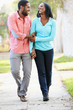 Photo: Couple Walking Along Suburban Street Together Couple Walking Along Suburban Street Together
