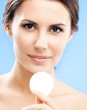 Young woman cleaning skin by cotton pad, over blue