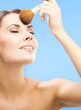 Woman with cosmetics brush, on blue