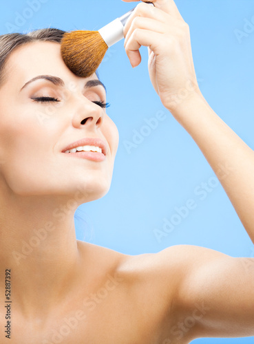 Photo: Woman with cosmetics brush, on blue Woman with cosmetics brush, on blue